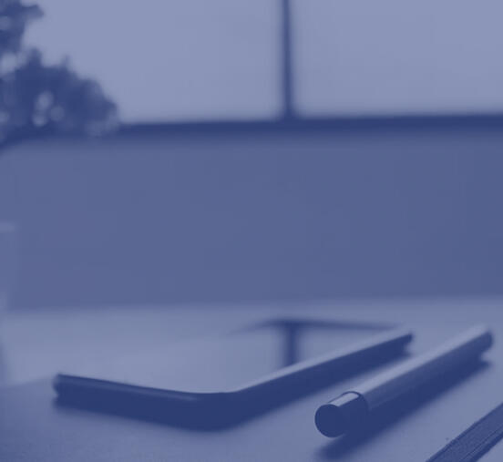 a mobile phone next to a pen on top of a table